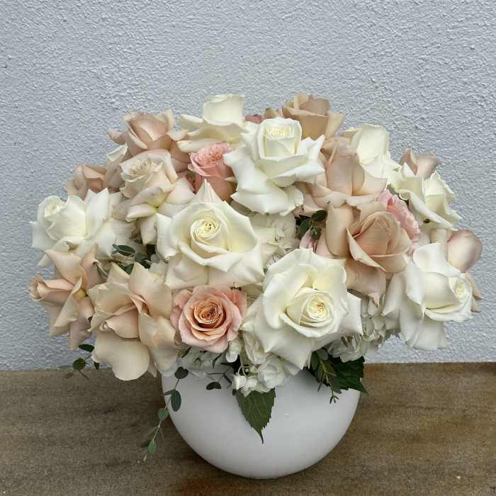 Cream and blush roses arranged in a white bowl vase
