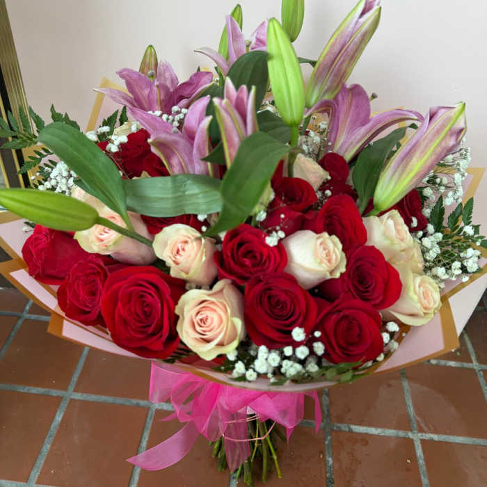 Bouquet of red and blush roses with pink lilies and baby's breath