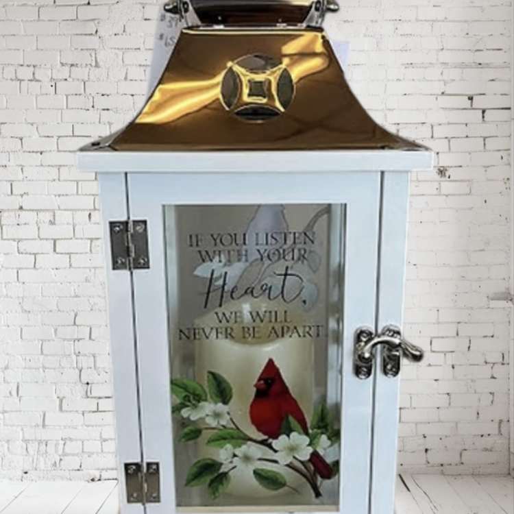 White lantern with a cardinal and floral design on the glass door