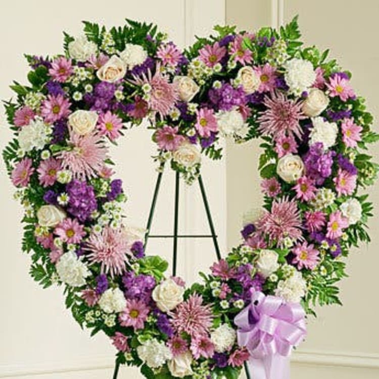 Heart-shaped floral wreath on an easel with pink, white, and purple flowers