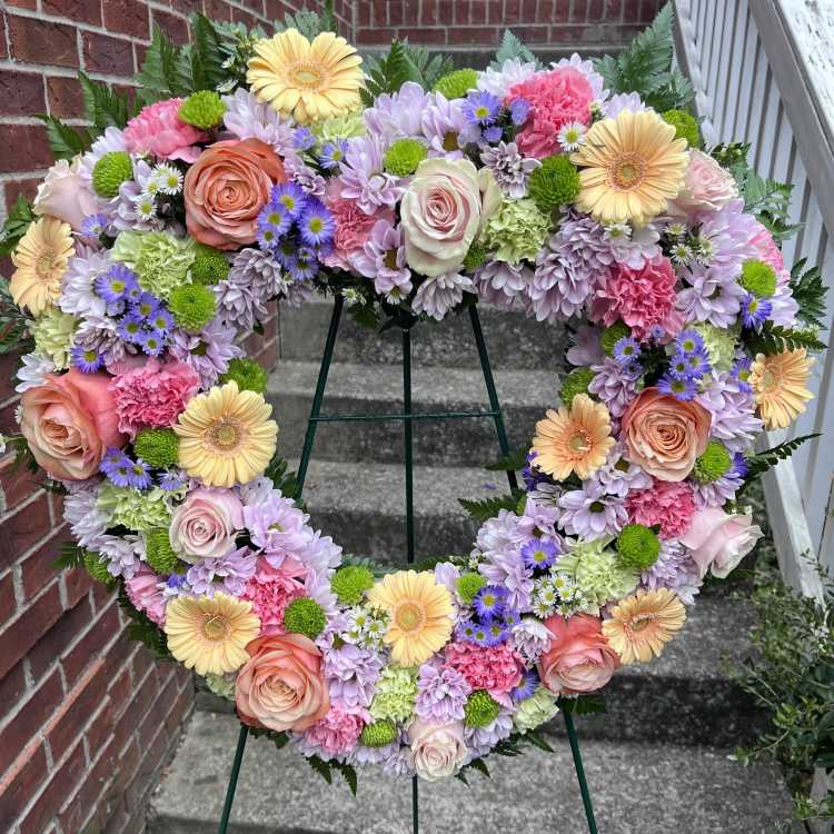 Heart-shaped floral wreath with pastel roses, daisies, and carnations