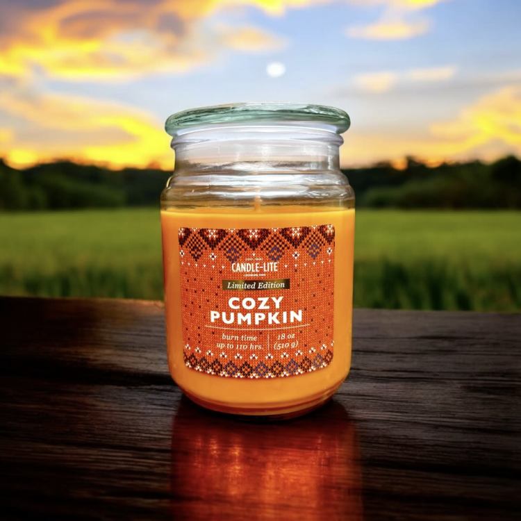 Orange pumpkin-scented candle in a glass jar with a lid