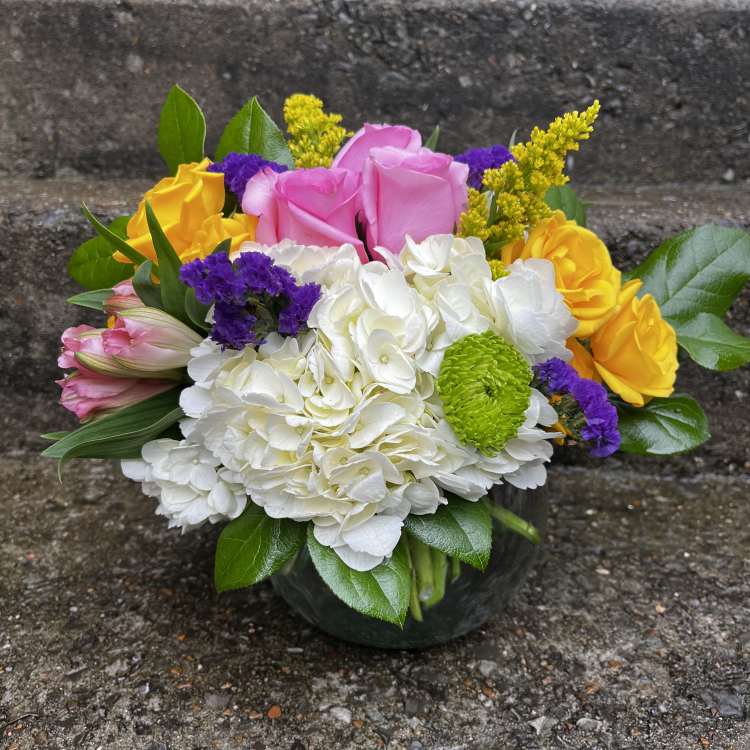 Colorful bouquet of roses, hydrangea, and mums in a glass vase
