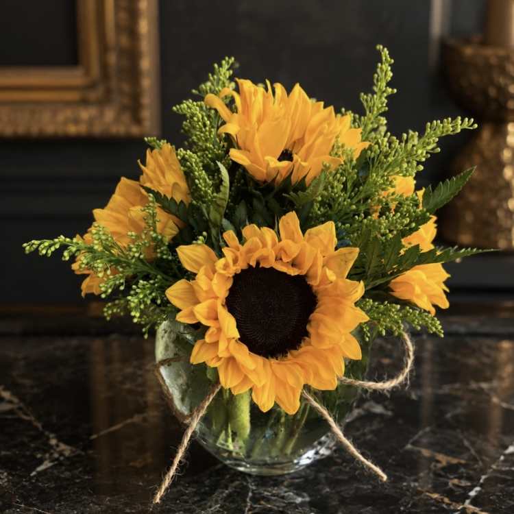 Sunflower bouquet in a clear glass vase with twine ribbon