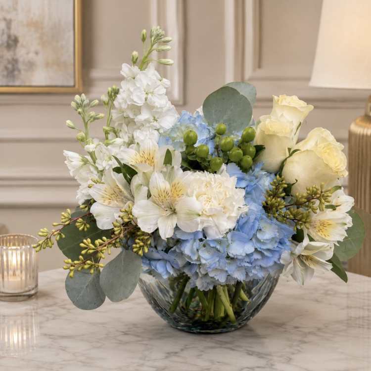 Blue and white flower arrangement in a glass bowl vase