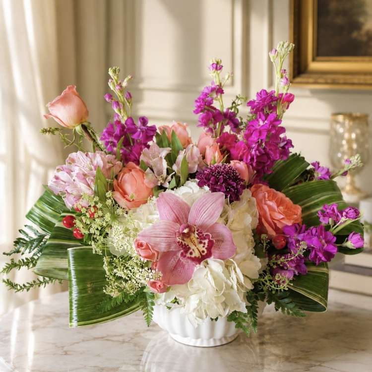 Pink and purple floral arrangement in a white vase