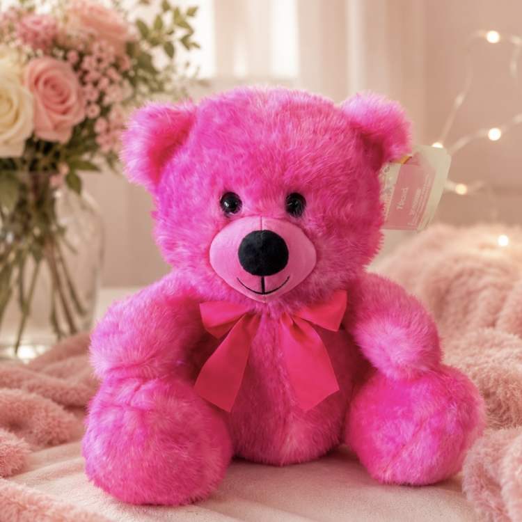 Bright pink teddy bear with a ribbon, sitting in front of a floral arrangement