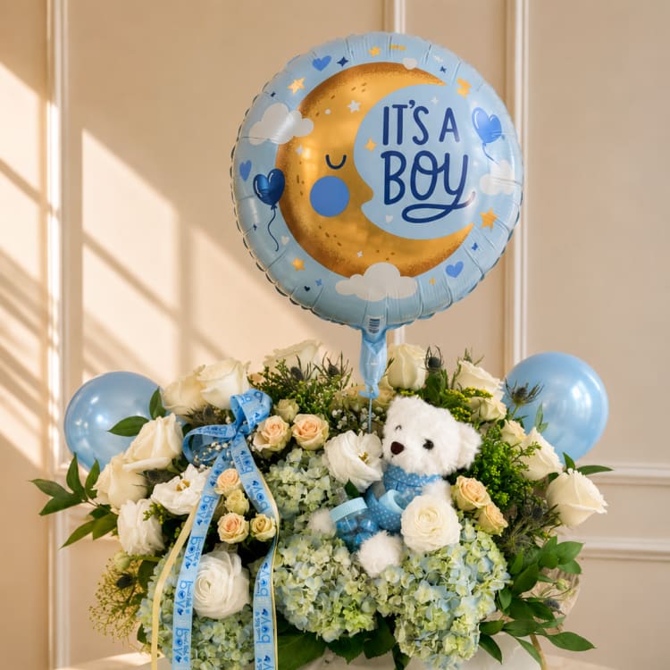 Blue baby boy balloon over white roses and hydrangeas with a teddy bear