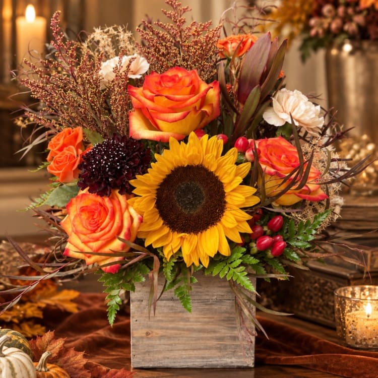 Orange roses and a sunflower in a wooden box arrangement