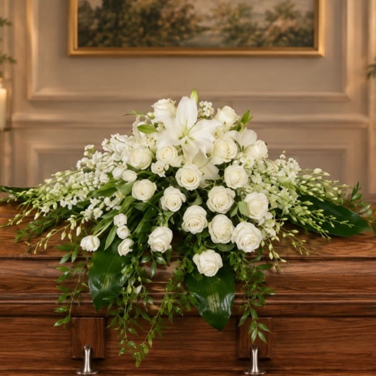 White roses and lilies arranged in a low casket spray