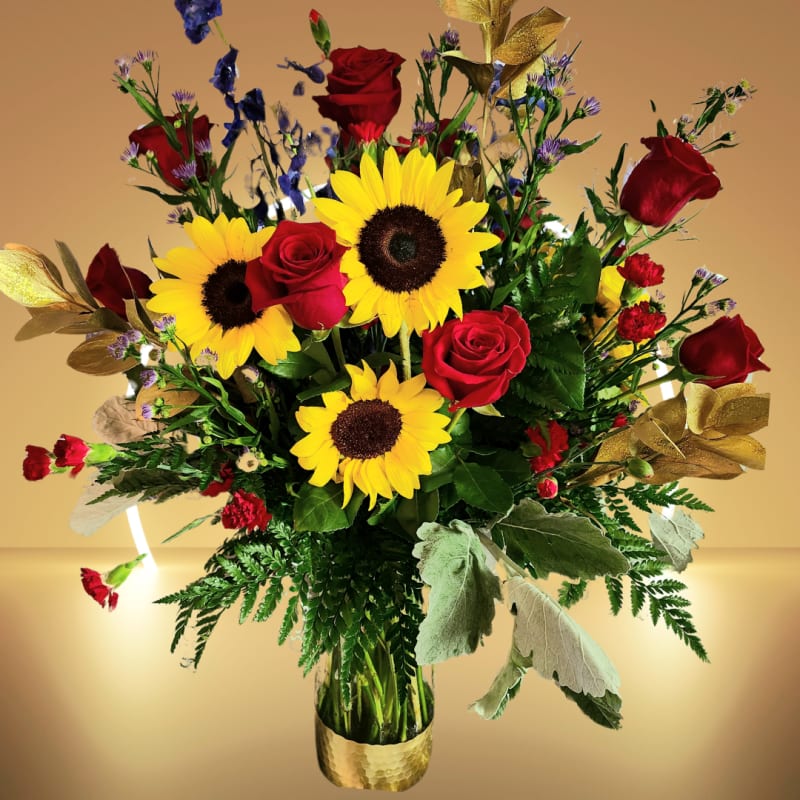 Bouquet of red roses and yellow sunflowers in a gold vase