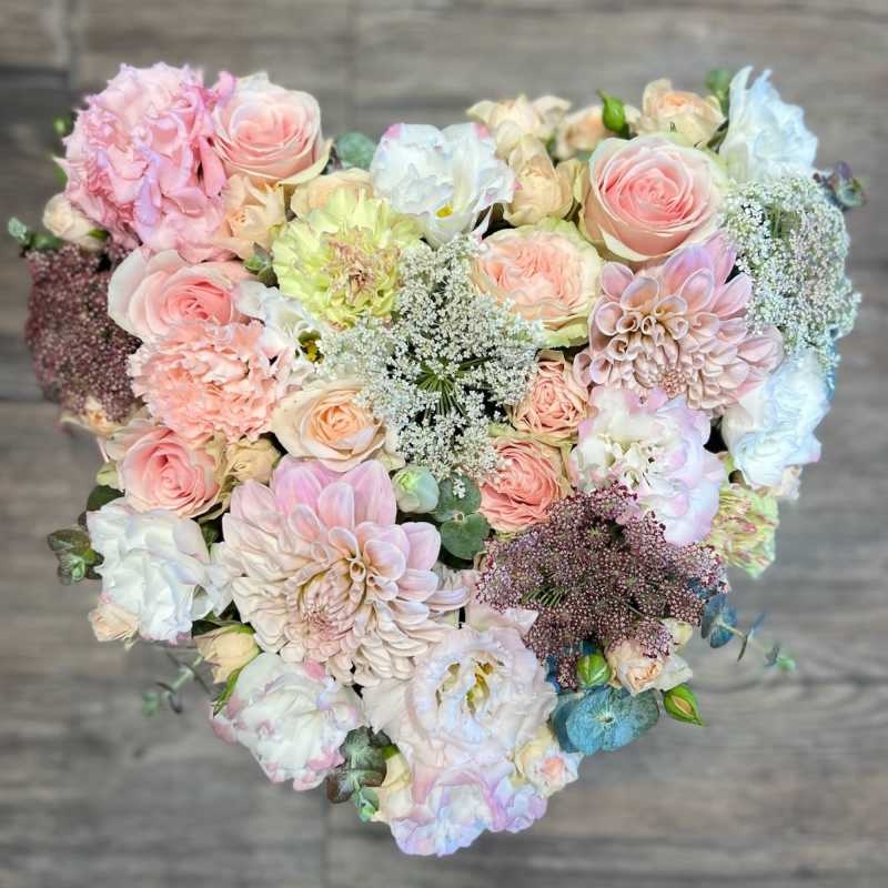 Heart-shaped bouquet of pastel roses, dahlias, and white filler flowers