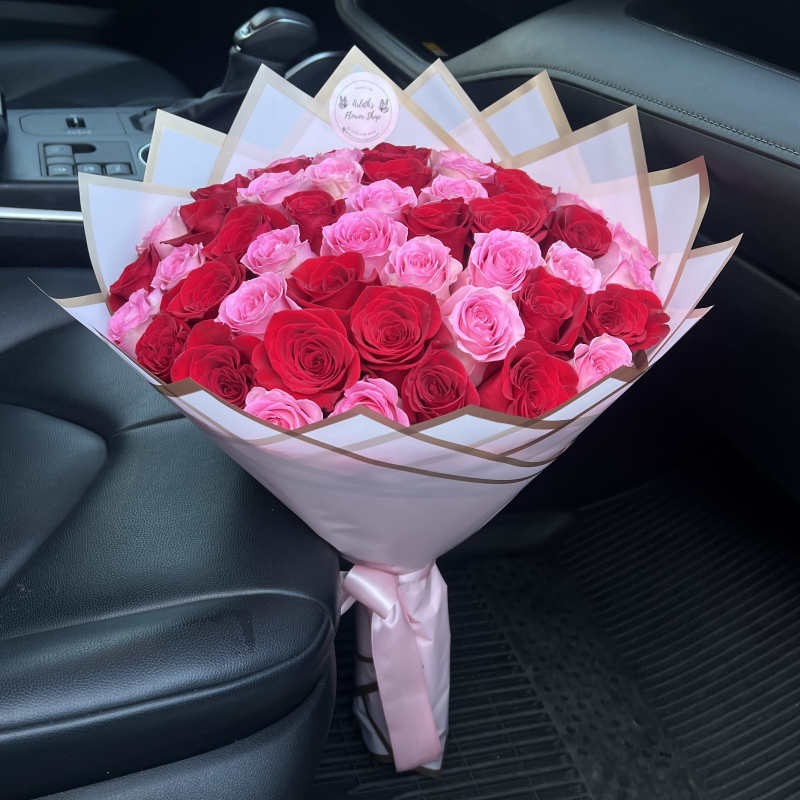 Large bouquet of pink and red roses wrapped in white paper