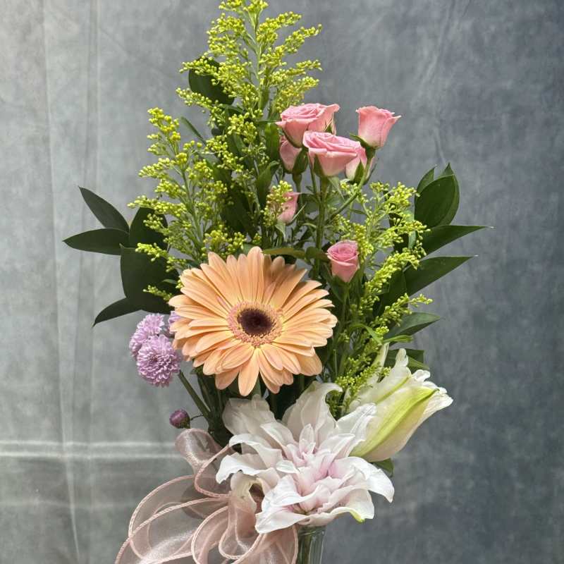 Mixed bouquet in a glass vase with pink roses, a peach gerbera, and white lilies