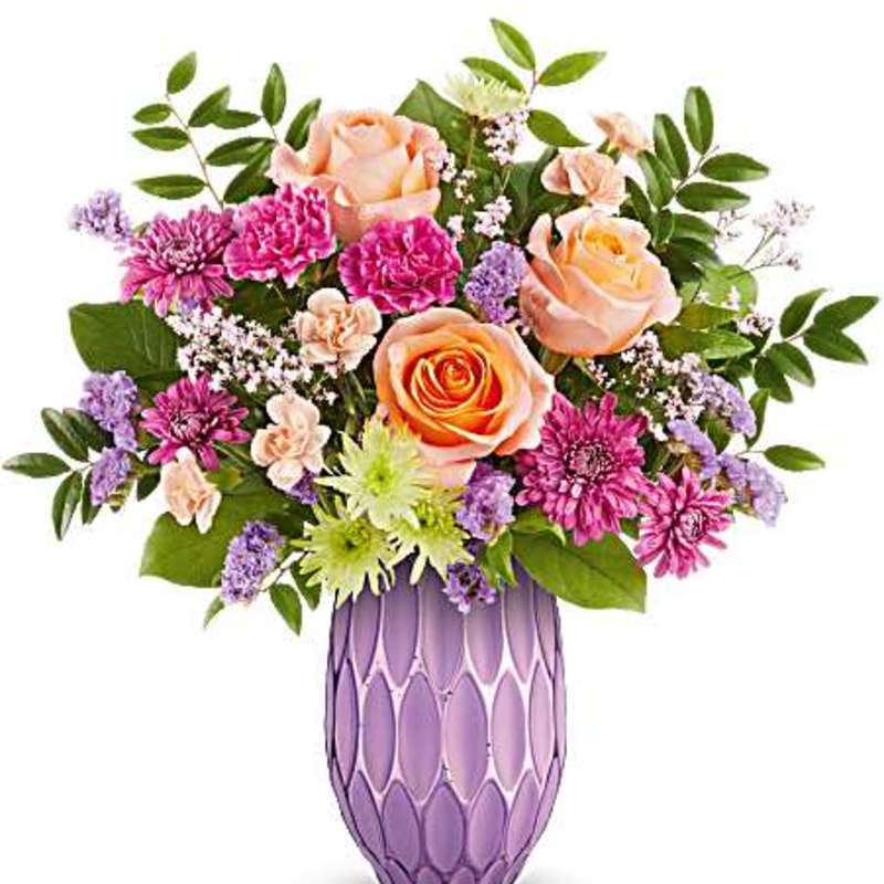 Bouquet of peach roses, pink chrysanthemums, and purple filler in a lavender vase