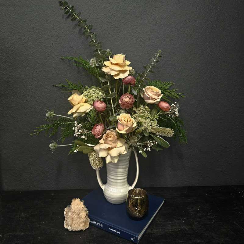 Arrangement of pale roses and pink ranunculus in a white vase