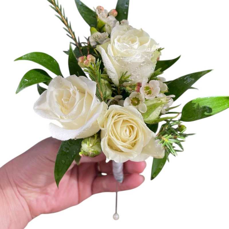 White rose boutonniere with small blossoms and glossy leaves