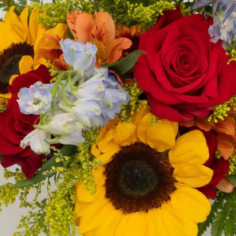 Bouquet of red roses and yellow sunflowers with blue flowers
