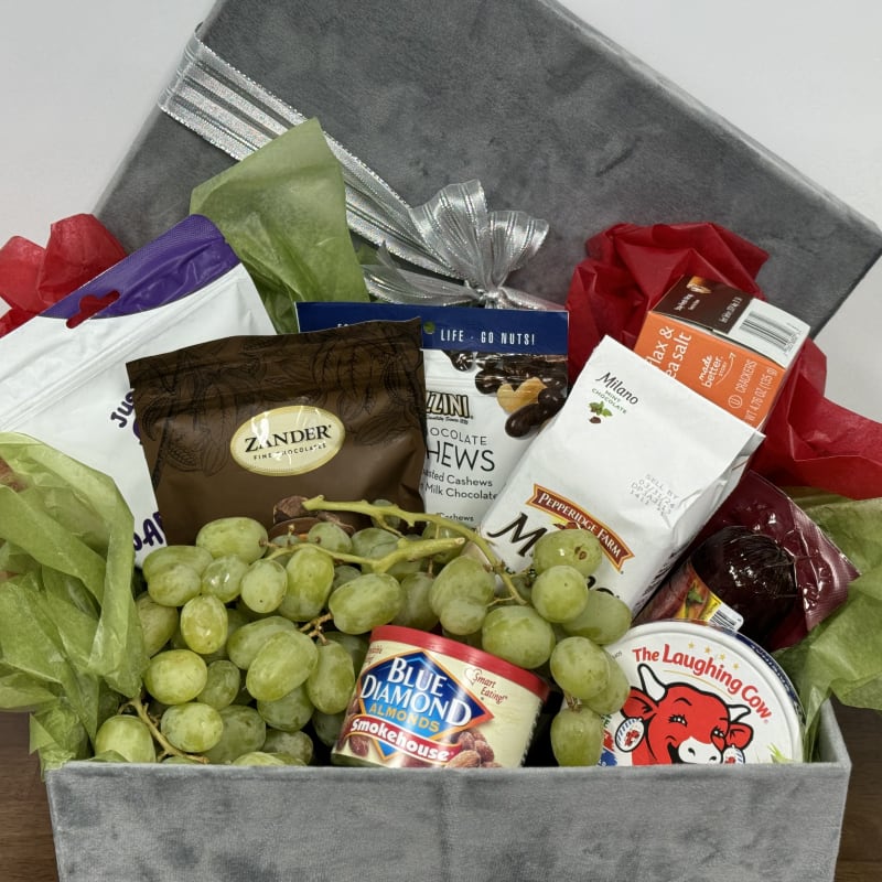 Gift basket with grapes, snacks, and a gray lid tied with silver ribbon