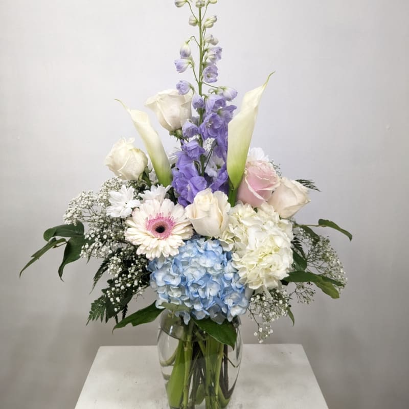 Tall pastel flower arrangement in a clear glass vase