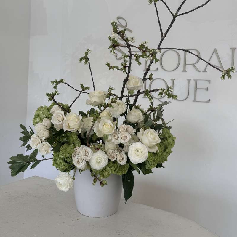 White floral arrangement in a white vase with branching stems
