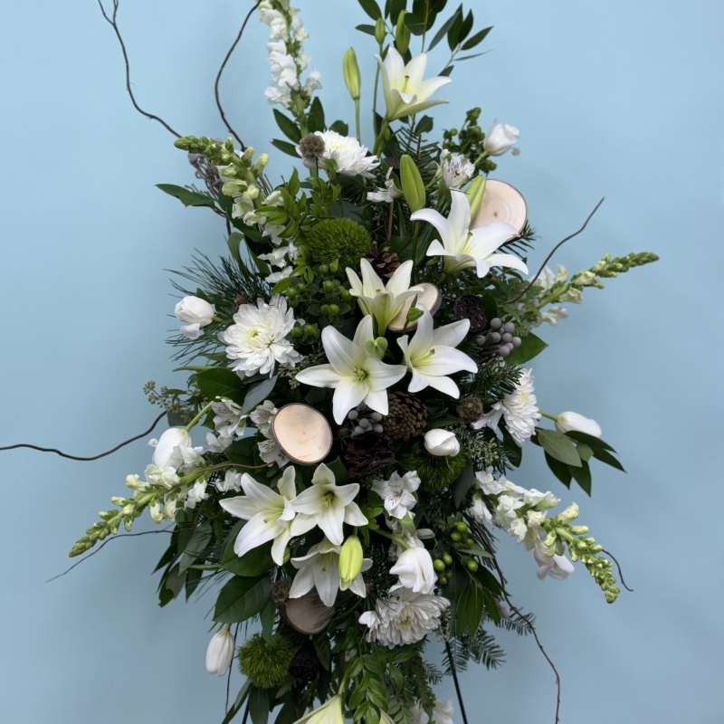 Tall white floral standing spray with lilies and mixed blooms on a frame