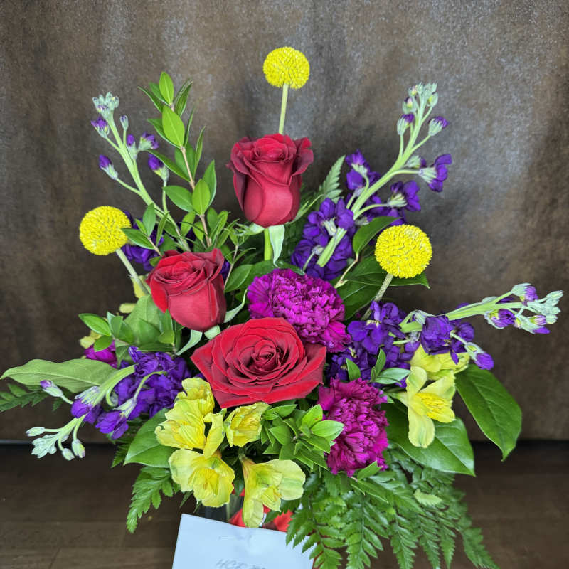 Bouquet of red roses, purple flowers, and yellow pom-pom blooms