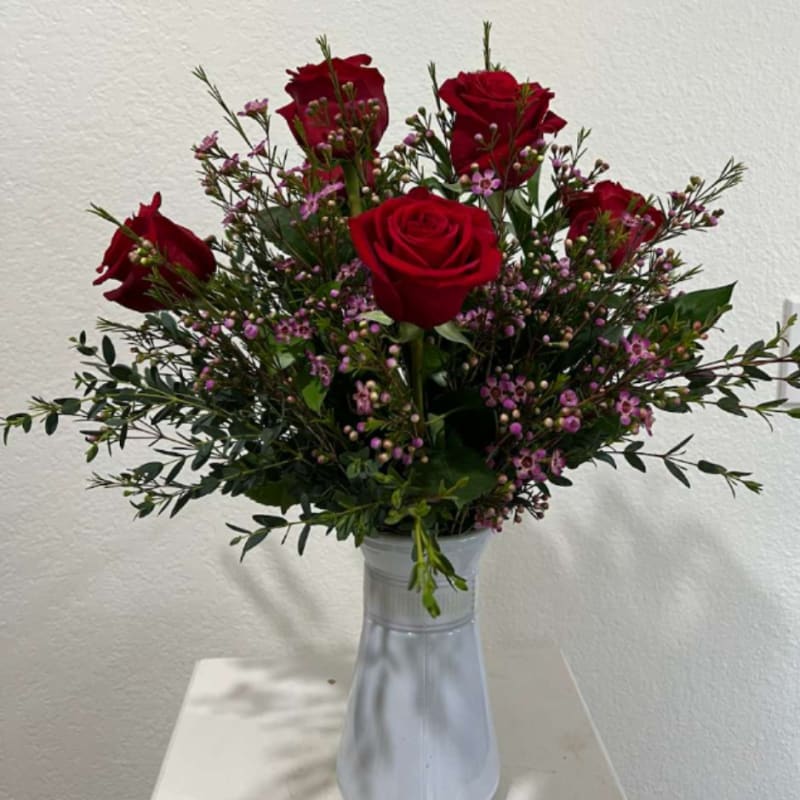 Red roses in a clear glass vase with small pink filler flowers