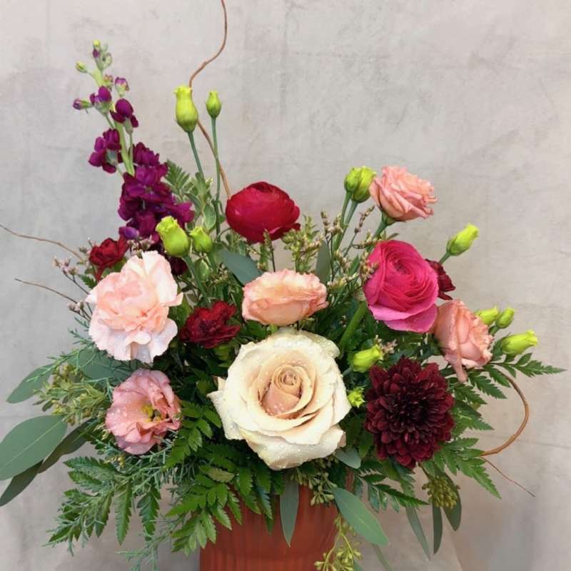 Mixed pink, cream, and burgundy flowers in a terracotta vase
