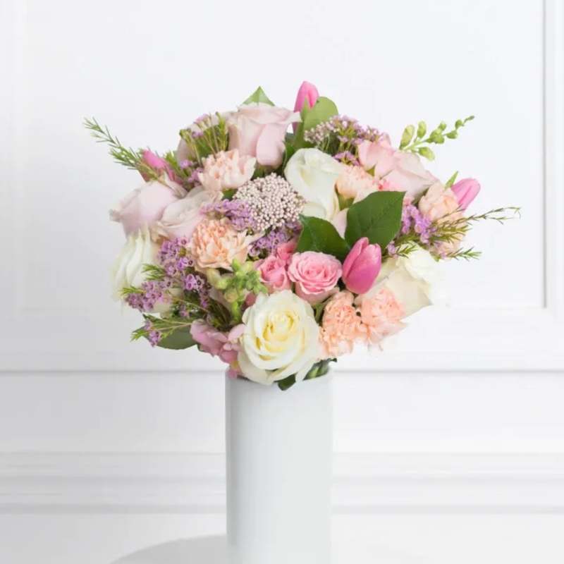 Pastel bouquet of roses, tulips, and carnations in a white vase