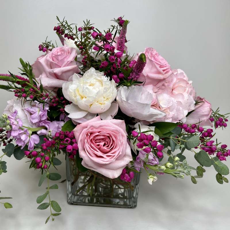 Pink and white floral arrangement in a square glass vase