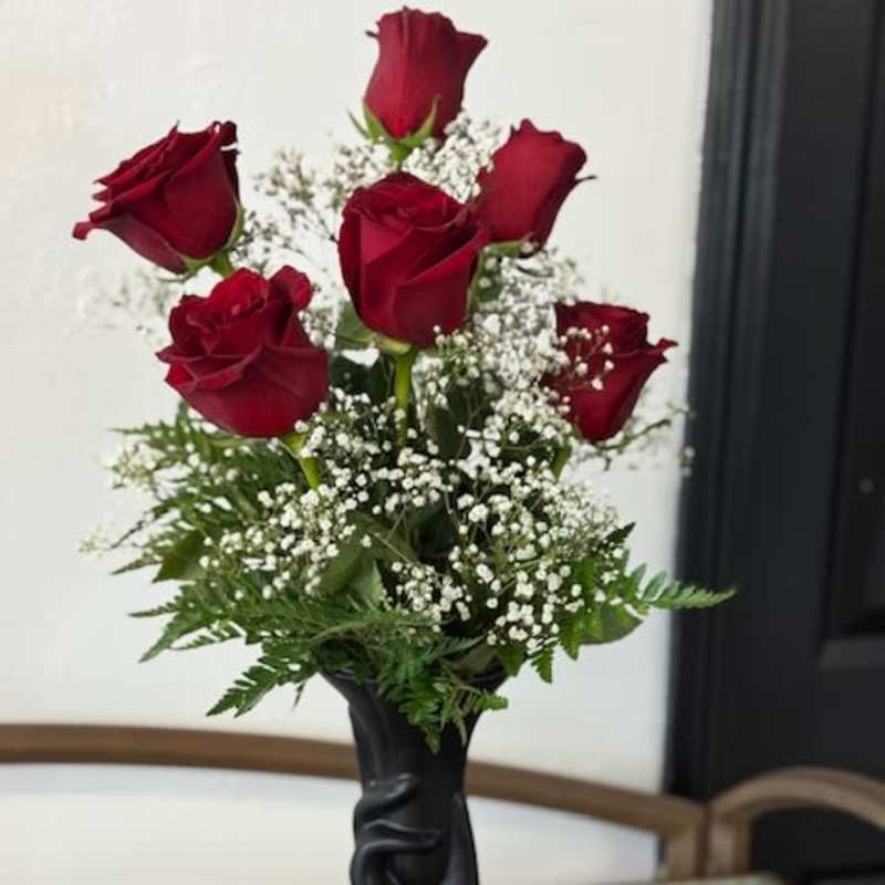 Red roses arranged in a black vase with white baby's breath