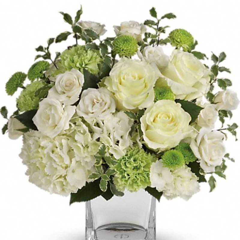 White roses and green mums arranged in a clear glass vase
