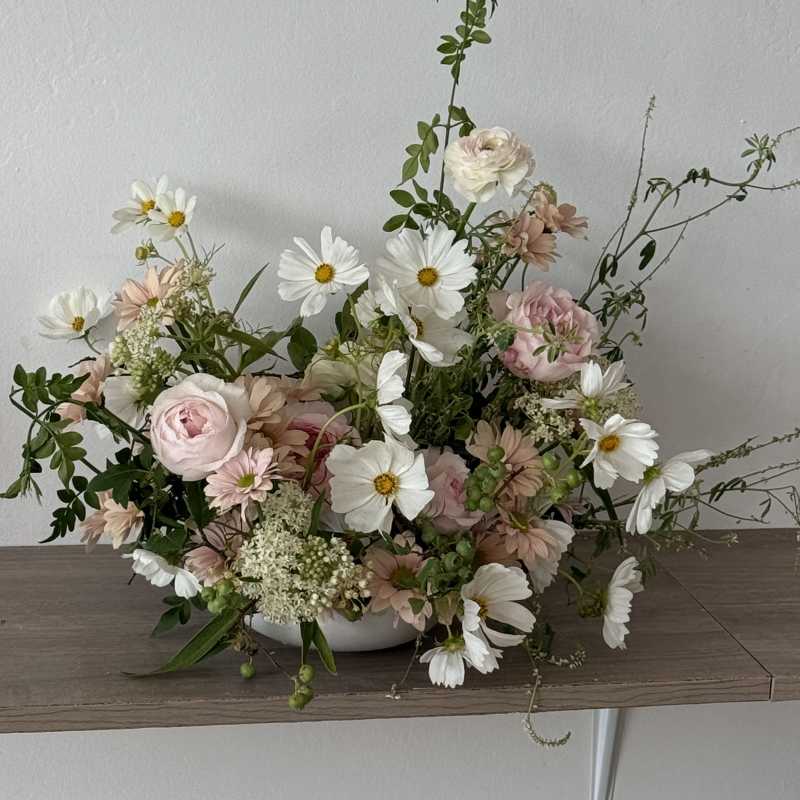 Low floral arrangement with pink and white blooms in a white bowl