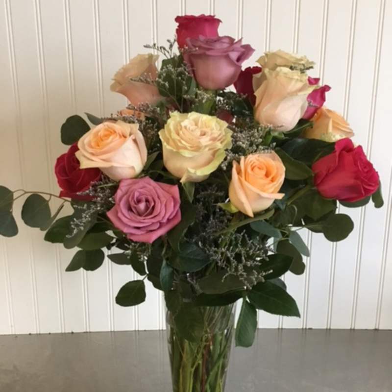 Mixed roses in a clear glass vase with greenery
