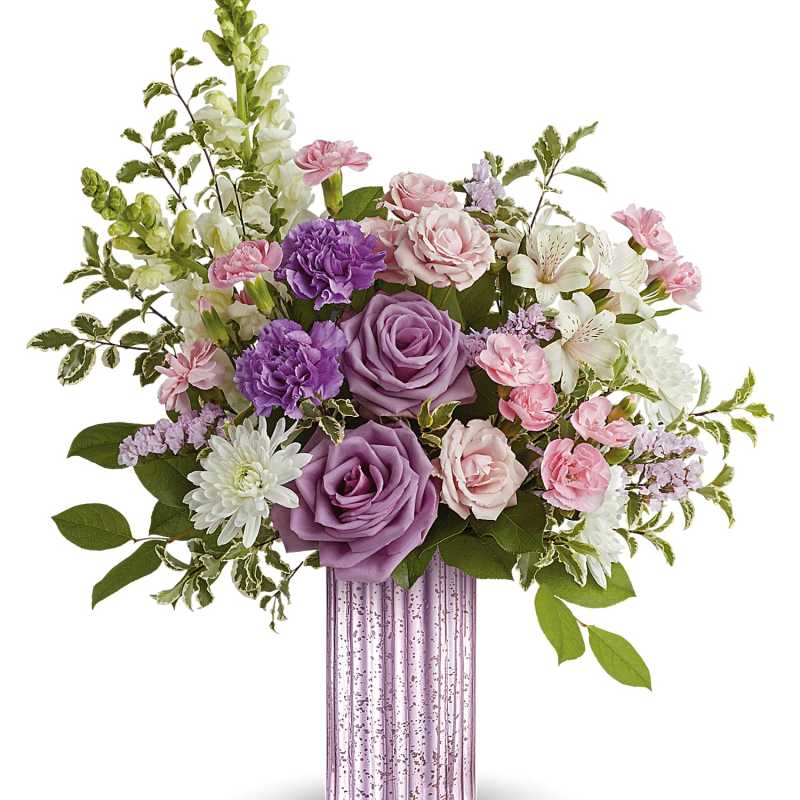 Lavender and pink flower arrangement with roses and carnations in a tall pink glass vase
