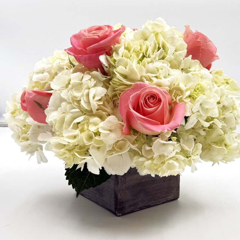 Pink roses arranged with white hydrangeas in a wooden box