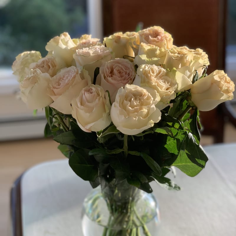 Bouquet of pale cream and blush roses in a clear glass vase