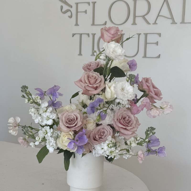 Pink and white rose arrangement in a white vase
