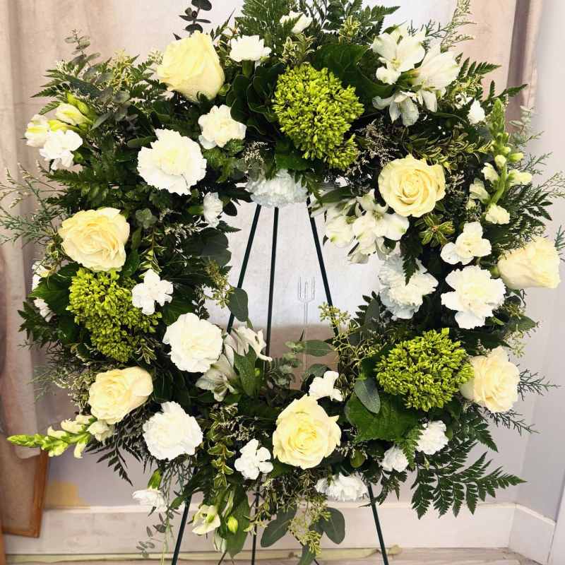 White and pale yellow floral wreath on a stand