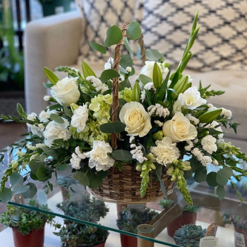 Basket arrangement of white roses, lilies, and carnations