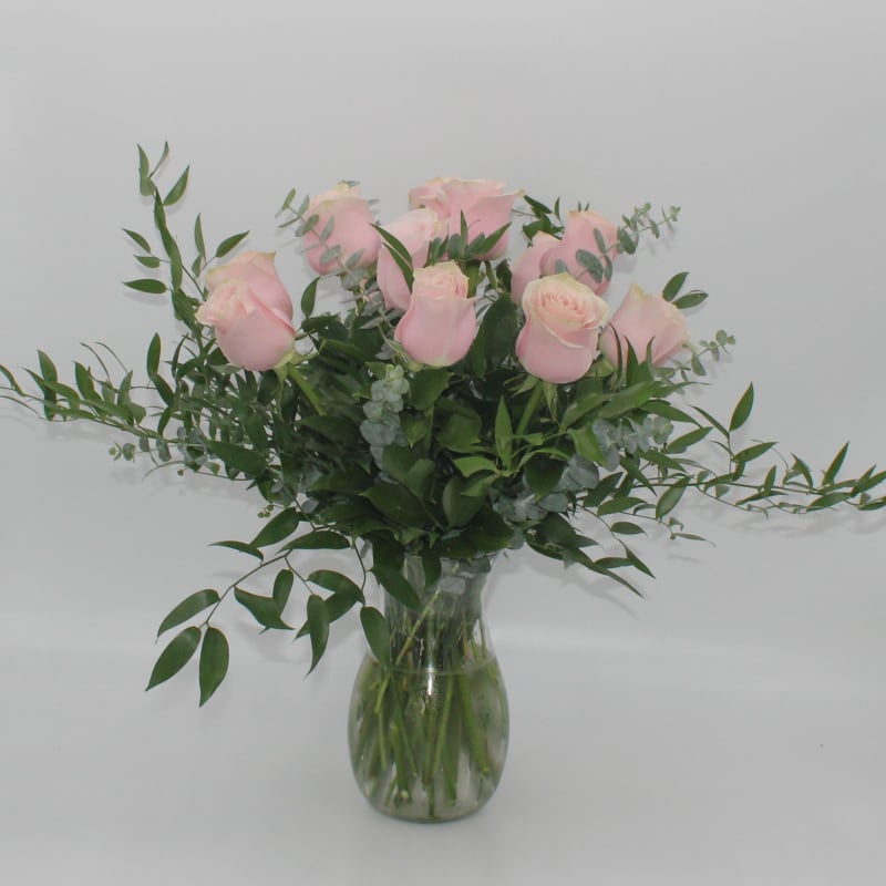 Pink roses in a clear glass vase with airy greenery