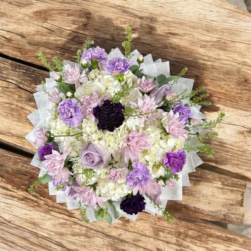 Lavender and white bouquet with carnations and hydrangeas wrapped in white paper
