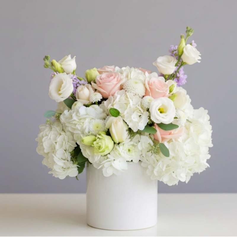 White and blush bouquet in a white cylindrical vase