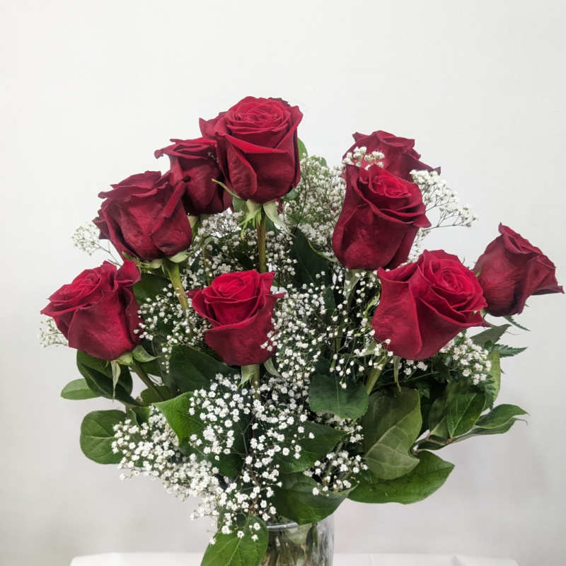 Red roses in a clear glass vase with white baby's breath