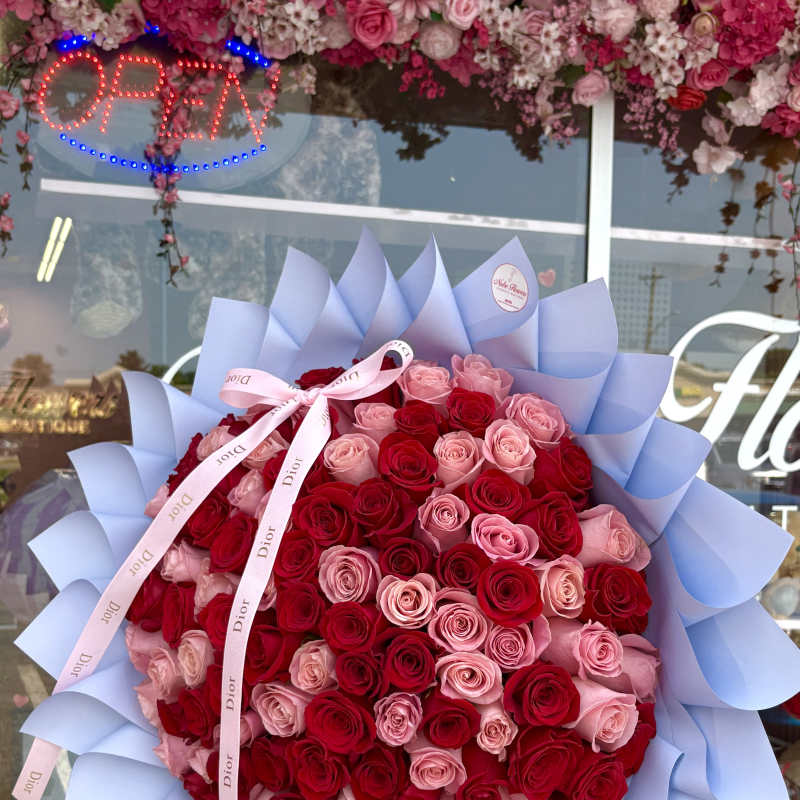 Large bouquet of red and pink roses wrapped in pale blue paper