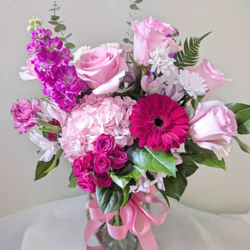 Pink and magenta mixed bouquet in a glass vase with a ribbon