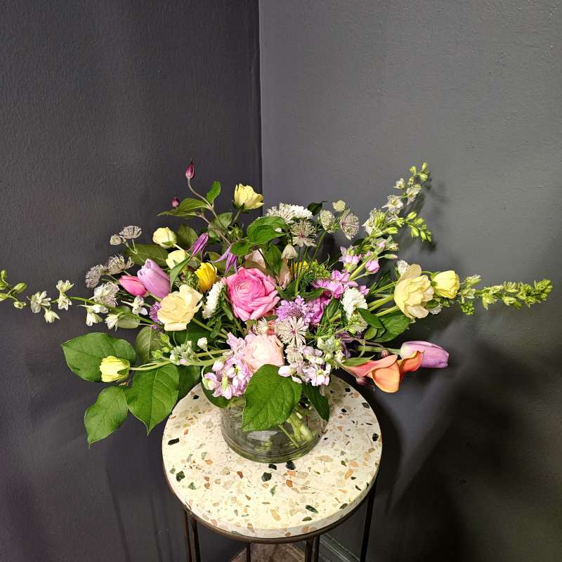 Mixed bouquet of pink, yellow, and white flowers in a glass vase