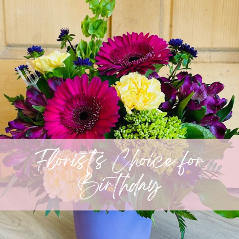 Bright mixed bouquet with magenta gerberas, yellow carnations, and purple blooms in a vase