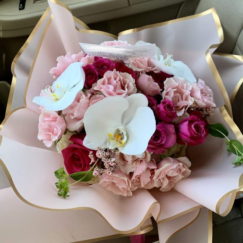 Pink and red rose bouquet with white orchids in pale wrapping